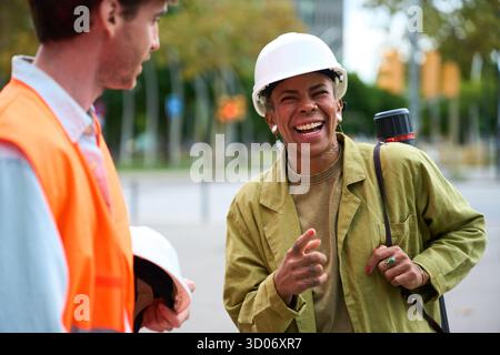 Construction engineers collaborating and laughing outdoors Stock Photo