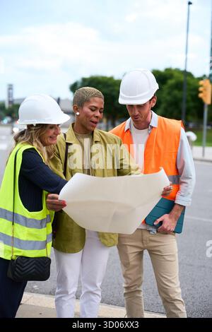 Diverse construction team reviewing blueprint on site Stock Photo