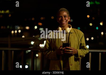 Young woman smiling using smartphone at night city Stock Photo