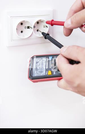 Measuring the voltage in the socket with a professional digital multimeter. Profession electrician, the process of installing sockets. Close-up, selec Stock Photo