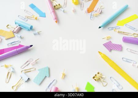 Colorful assortment of office supplies including pens, markers, paper clips and paper clips scattered on a white background. The overall mood is brigh Stock Photo