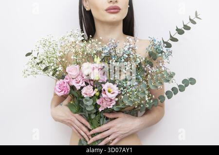 The girl's hands are holding a very beautiful spring bouquet of flowers: pink eustoma, gypsophila multicolored, eucalyptus. Flower composition. Spring Stock Photo