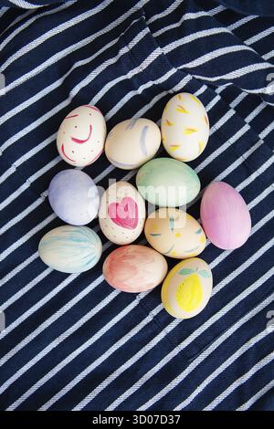 Beautiful Easter eggs painted with watercolors lie on a striped blue fabric Stock Photo