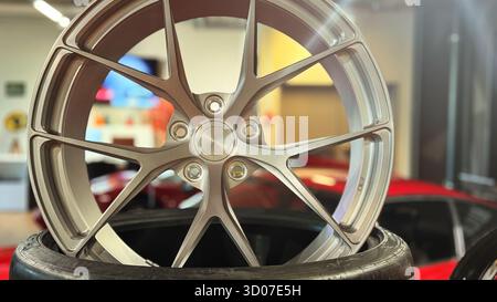 Premium silver alloy rim for modern sport car on display. Custom aluminum automobile wheel and tire detail. Luxury automotive tuning and shop concept Stock Photo