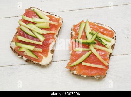 Two open sandwiches with red fish and cucumber on wooden background Stock Photo
