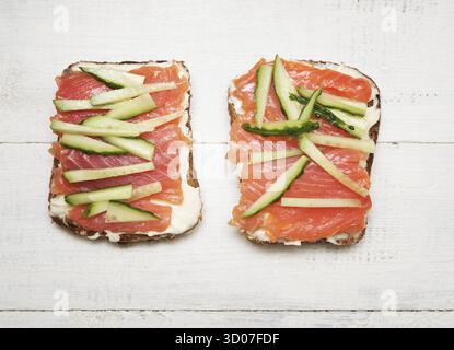 Two open sandwiches with red fish and cucumber on wooden background Stock Photo