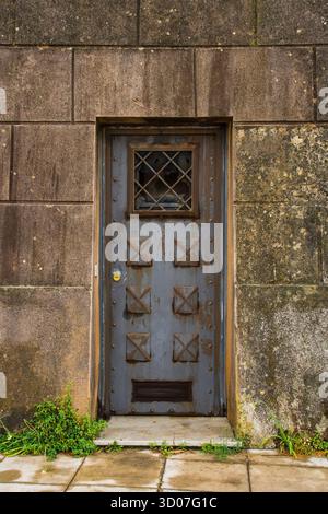 A metal door at the Foro Italico waterfront in Palermo, Sicily, Italy. A mid-20th century utilitarian rusting door with weathered gray-blue paint Stock Photo