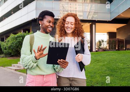 two young women smiling while using a tablet Stock Photo