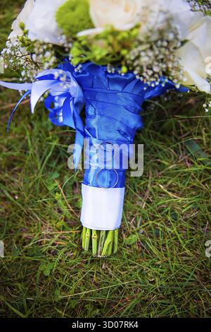 Wedding rings and bridal bouquet lying on a green grass Stock Photo