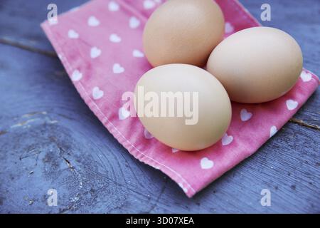 Eggs on pink tablecloth over grunge blue wooden background Stock Photo