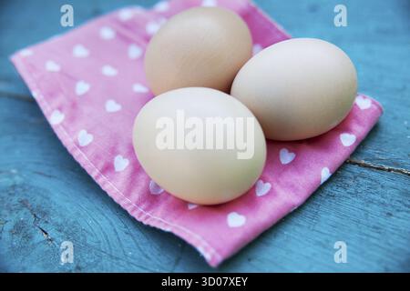 Eggs on pink tablecloth over old blue wooden background Stock Photo