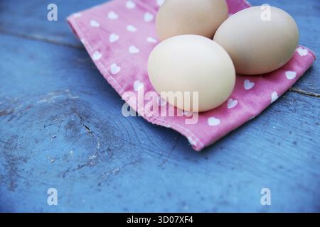 Eggs on pink tablecloth over vintage blue wooden background Stock Photo