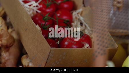 Displaying cherry clusters on vine in cardboard crate on wood shavings with ginger root pieces Stock Photo