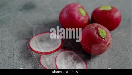 Arranging three red radishes and two radish slices on kitchen countertop, fresh produce Stock Photo