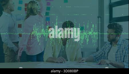 Collaborating coworkers placing sticky notes and reviewing charts in meeting room, planning session Stock Photo