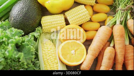 Showcasing fresh produce on kitchen counter, featuring kale, avocado, corn, carrots and oranges Stock Photo