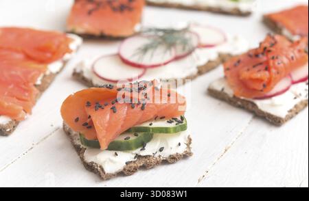 Canapes with salmon and vegetables on a wooden background Stock Photo