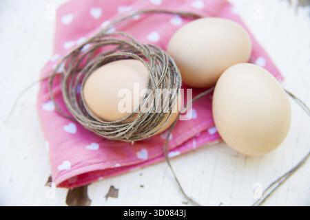 Three eggs on the table on a rose napkin Stock Photo