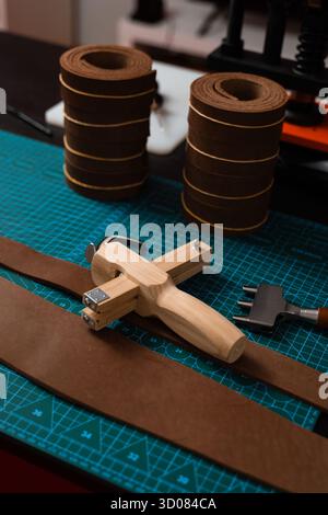 Leatherworking setup featuring tools, buckle, and leather strips laid out neatly on a mat, ready for belt making. Leathercraft tools and belt-making p Stock Photo