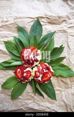 Beautiful and bright cupcakes with strawberries lie on green leaves Stock Photo
