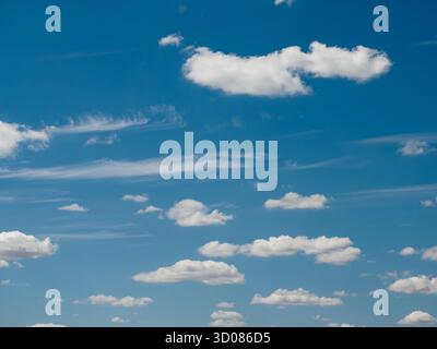 Scenic view of fluffy white clouds floating across a bright blue sky, creating a peaceful and natural background Stock Photo