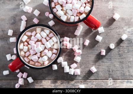 Hot chocolate drink with marshmallows in red mug on wooden table Stock Photo