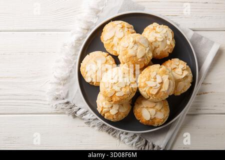 Crispy shortbread cookies with almond flakes close-up in a plate on a wooden table. Horizontal top view from above Stock Photo