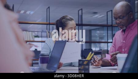Reviewing report and writing on pink sticky notes, coworkers sitting at office table with laptop Stock Photo
