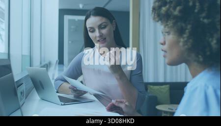 Reviewing documents two business casual colleagues discussing project at office, with silver laptop Stock Photo