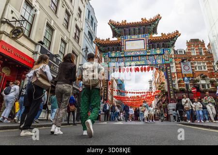 London Chinatown with lanterns and traditional paifang arch, busy crowd. London, UK, 16 July 2023 Stock Photo