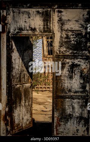 Old House With Rusty Window Grate And Blue Patterned Cloth Hanging Outside: Vintage Urban Scene With Weathered Walls And Faded Architecture In Tbilisi Stock Photo