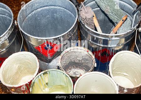 Empty paint buckets containing used rollers and brushes Stock Photo
