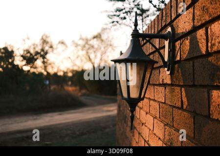 Vintage wall lantern on brick wall glowing in warm sunset light Stock Photo