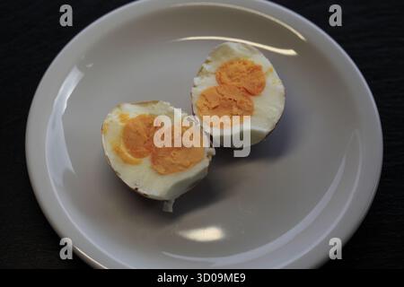 view from above on a rare half boiled chicken egg with double yolk on a white plate. Photo by Willy Matheisl Stock Photo