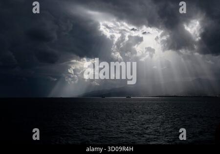 Sunlight breaking through the clouds, seen from the ferry between Calabria and Sicily in Italy Stock Photo