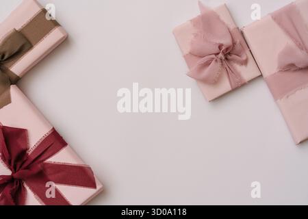 Minimal aesthetic composition with pastel pink gift boxes wrapped in fabric ribbons, placed on a light neutral background. Cozy and elegant flat lay w Stock Photo