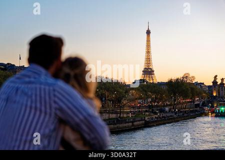 France, Paris, the banks of the Seine, classified as UNESCO World Heritage, a couple embracing looking at the illuminated Eiffel Tower (© SETE-illuminations Pierre Bideau) Stock Photo