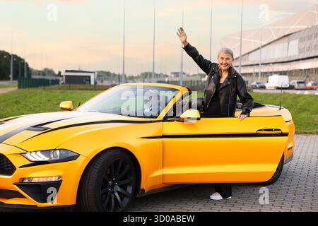 Stylish woman getting out of modern cabriolet outdoors Stock Photo