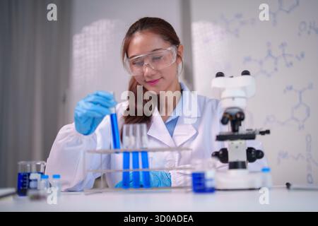 Diligent young Asian woman scientist engaged in advanced laboratory research handling samples with precision for innovation and discovery in science. Stock Photo