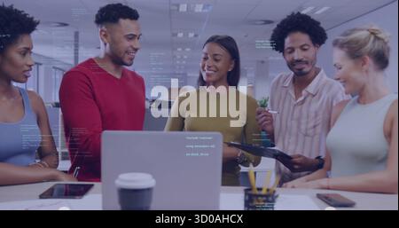 Collaborating office colleagues discussing project on laptop and clipboard in open-plan workspace Stock Photo