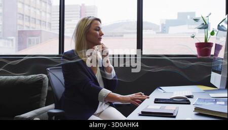 Resting businesswoman hovering over mouse at modern office desk, with monitor smartphones notebook Stock Photo