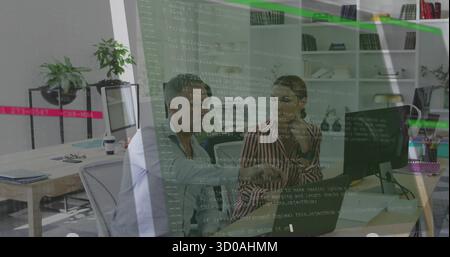 Developers in striped blouse and blue shirt reviewing code on monitor in office, with laptop Stock Photo