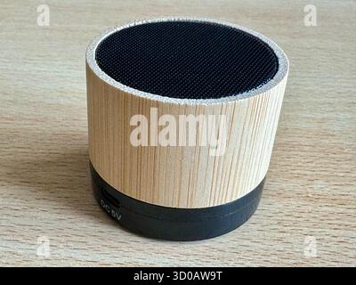 Bamboo Bluetooth speaker on wooden surface showing DC 5V charging port. Stock Photo