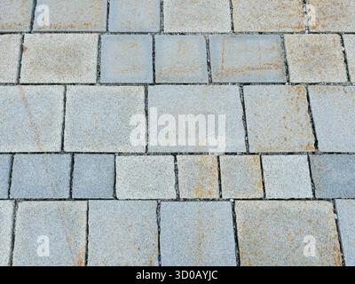 Granite pavement in gray tones with irregular pattern and natural patina. Close-up. Copyspace. Stock Photo
