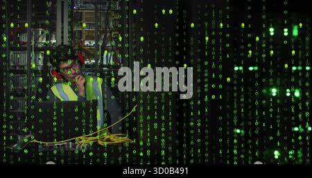 Using laptop with cables in server room under green overlay wearing vest and protectors, copy space Stock Photo