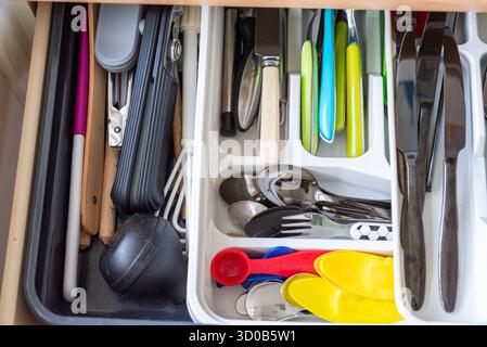 Authentic kitchen cutlery drawer with organiser. Knives, forks, spoons, implements. Metal and plastic utensils Stock Photo