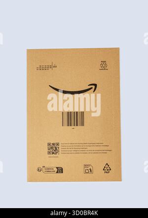 Padova, Italy - September 18, 2025: Amazon packaging box with barcode and logo displayed on a plain blue background, showcasing e-commerce delivery an Stock Photo