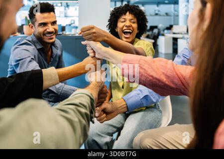 Diverse business team smiling while stacking fists together at office Stock Photo