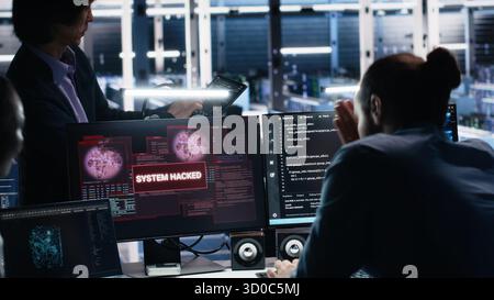Engineers in AI server hub alerted by hacking incident involving theft of sensitive data. Teamworking data center employees alarmed by computer virus triggered by security systems, camera A Stock Photo