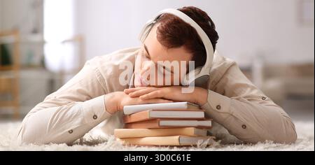Young male student sleeping while listening to audiobook at home Stock Photo